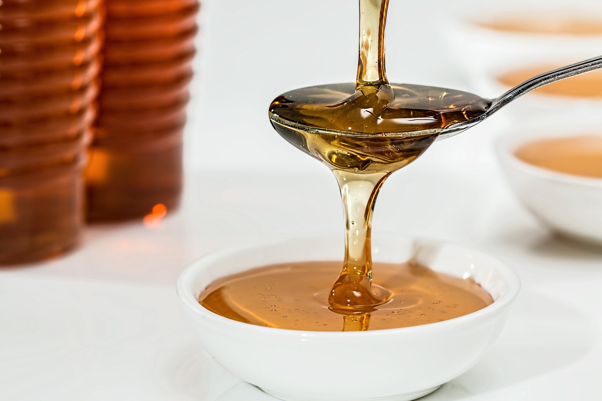 honey being poured into a spoon and into a bowl