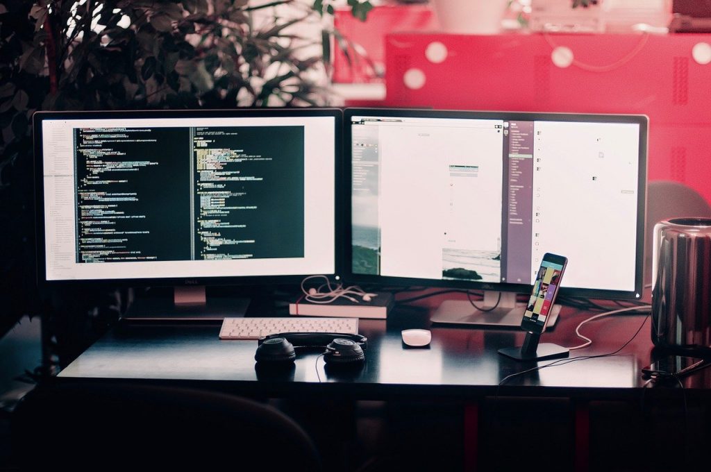 Desk with two monitors and a cell phone