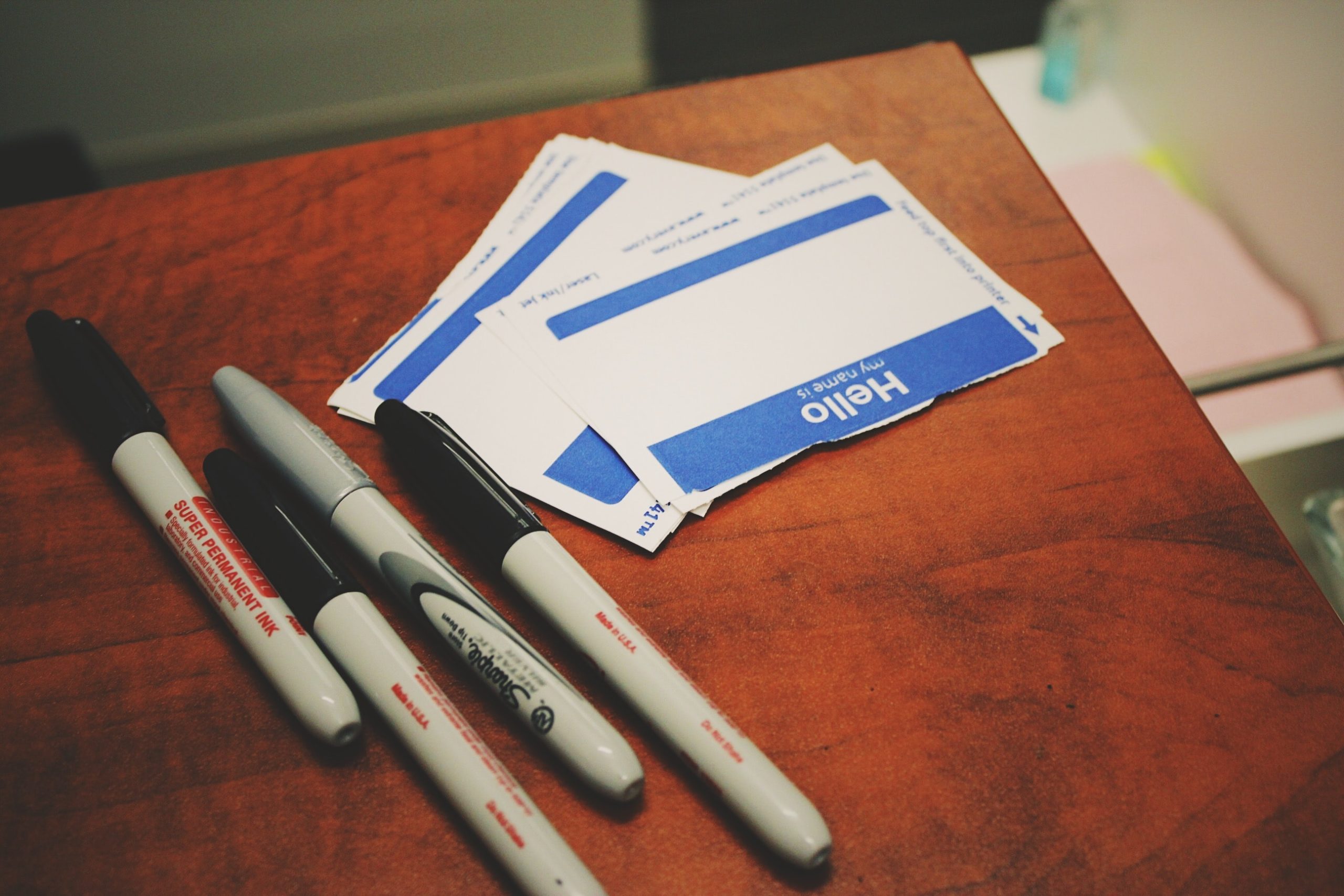 Name tags and black markers on a wooden table