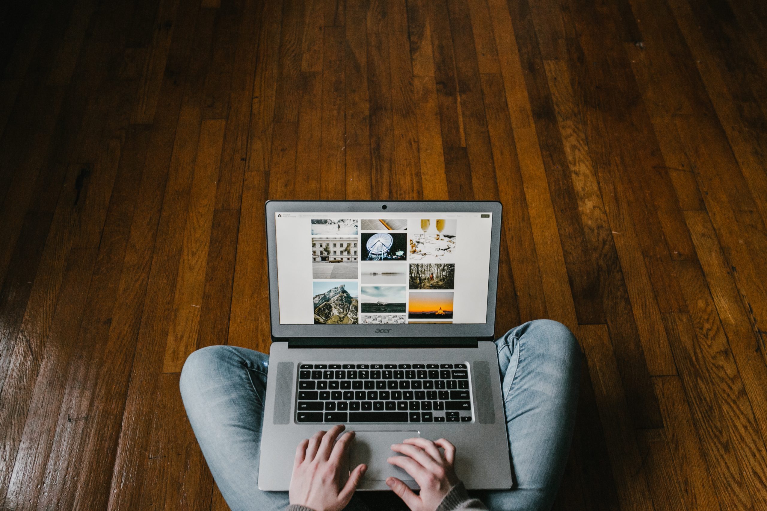 person sitting on hardwood floor with a laptop on their lap